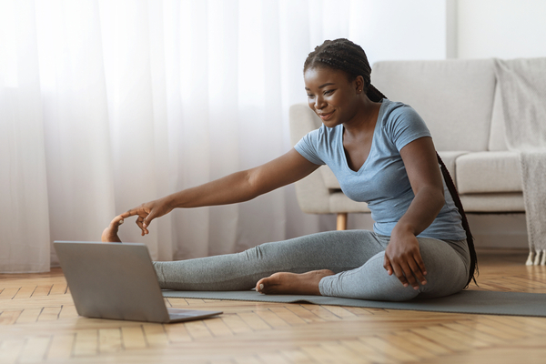A woman stretching indoors in front of a computer 