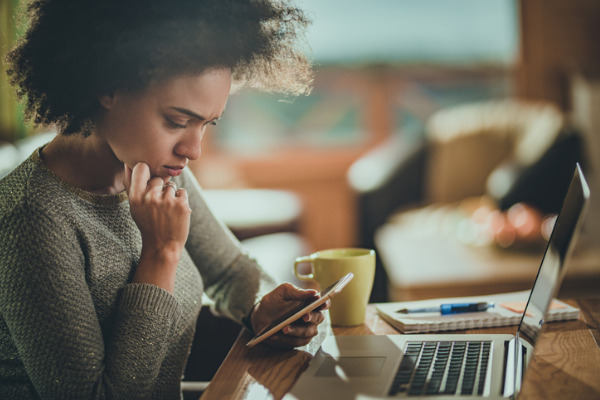 concerned woman looking at phone working from home