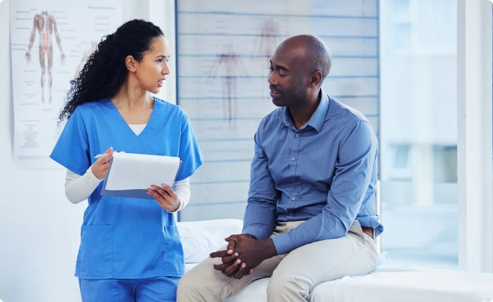 A nurse or doctor consulting with a patient in an exam room.